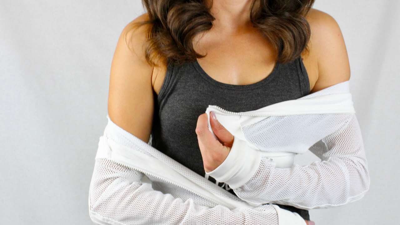 Woman wearing a dark tank top under a white, mesh jacket off her shoulders, exposing her acne-free upper chest and shoulders.