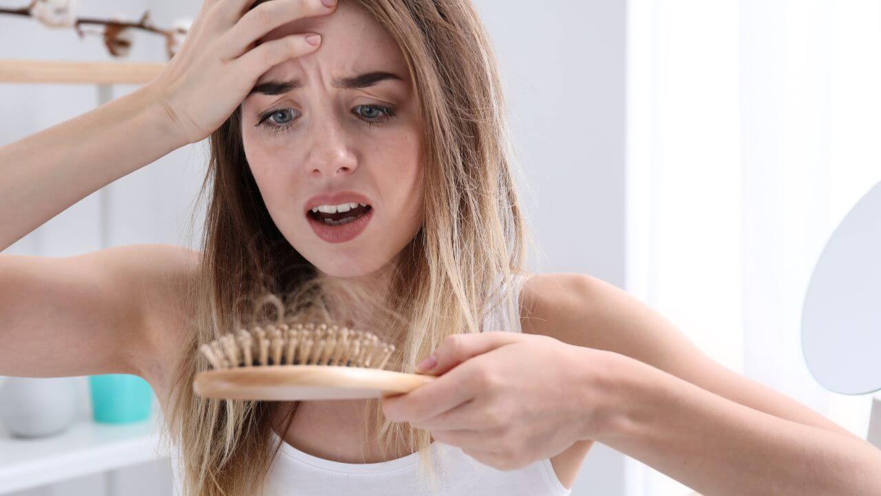 Woman with thinning hair is concerned at the amount of shedding after brushing her hair which are common signs of aging. 
