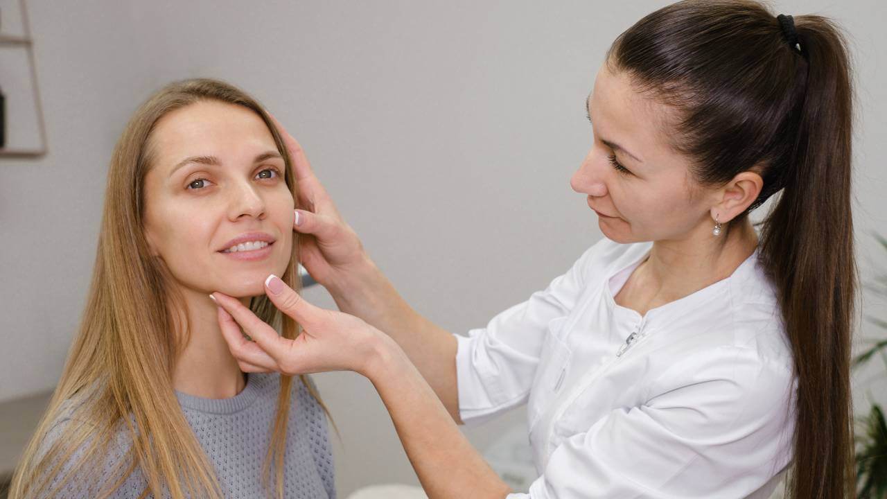 Dermatologist using her hands to examine the side effects of a patient using acne medicines on the surface of the skin.