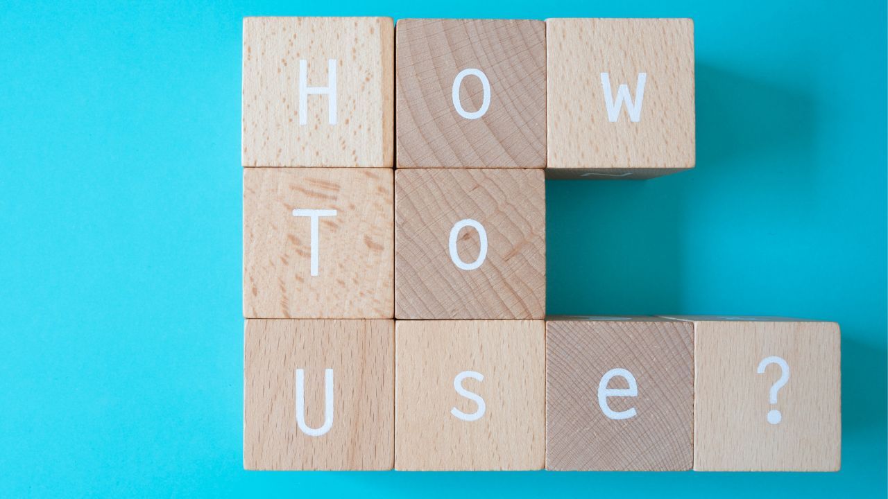 9 wooden building blocks that spell “How To Use?” in white letters on a teal colored background.