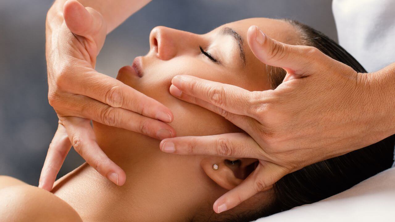 Young woman receiving a facial massage from a healthcare provider to prevent expression lines. 