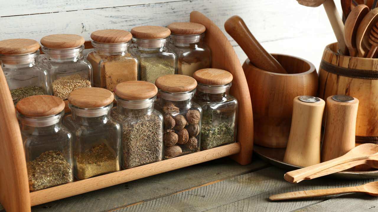 Wooden spice rack with 10 spice bottles including nutmeg powder.