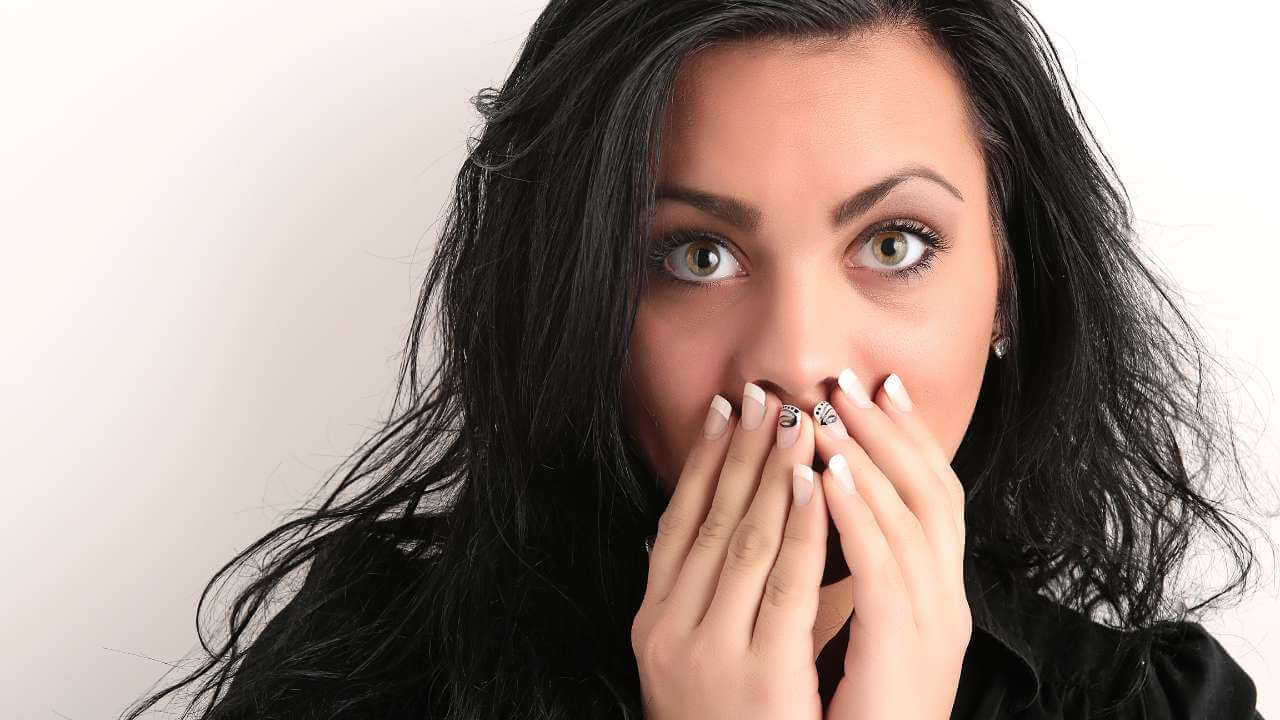 Embarrassed woman covers darkened areas of skin around the mouth with both hands.