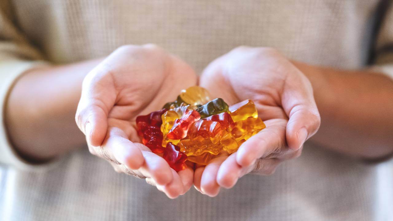 Person holding handfuls of colorful, organic Irish sea moss gummies in open palms.