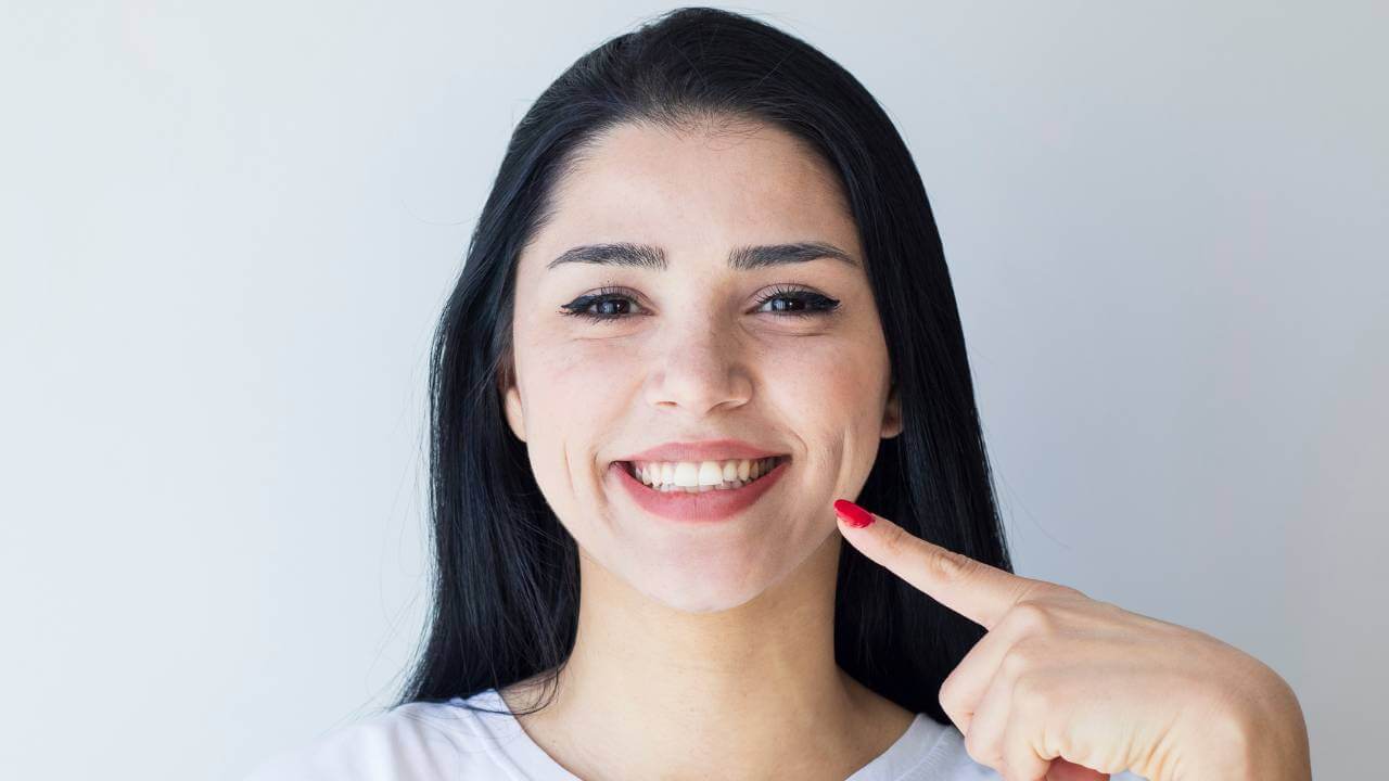 A woman pointing to her smile lines and laugh lines around her eyes and mouth.